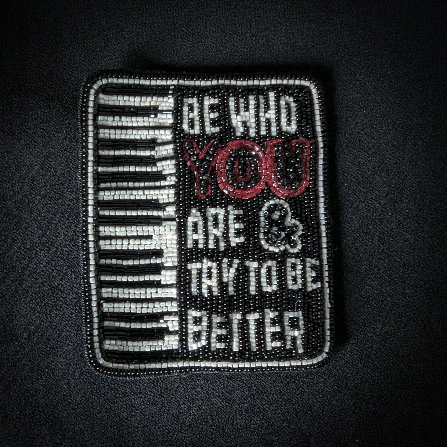 Black and white beaded patch with piano keys and "BE WHO YOU ARE & TRY TO BE BETTER" text.