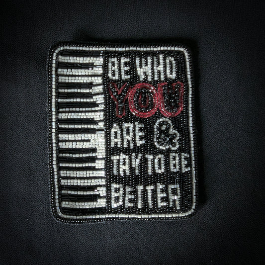 Black and white beaded patch with piano keys and "BE WHO YOU ARE & TRY TO BE BETTER" text.