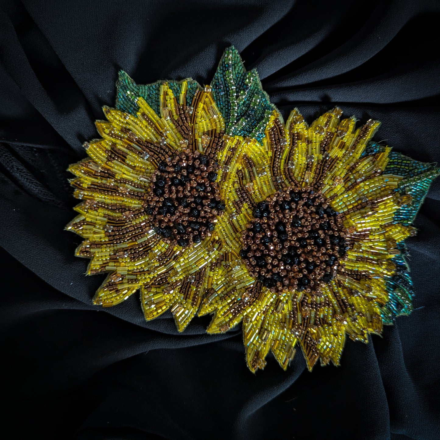 Beaded D&G sunflower patch, yellow and brown with green leaves, on black fabric.