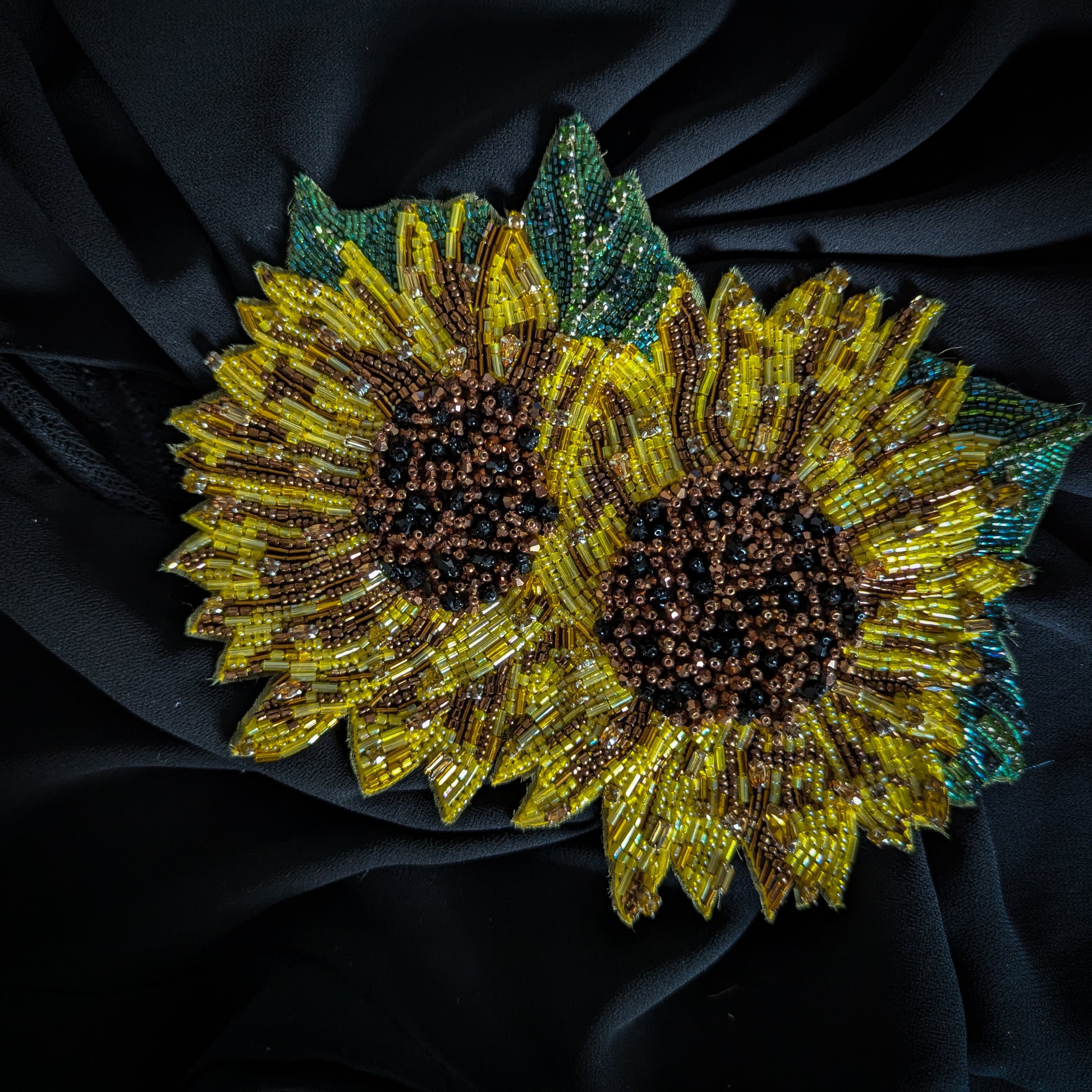 Beaded D&G sunflower patch, yellow and brown with green leaves, on black fabric.