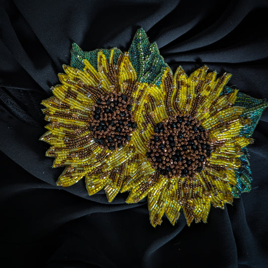 Beaded D&G sunflower patch, yellow and brown with green leaves, on black fabric.