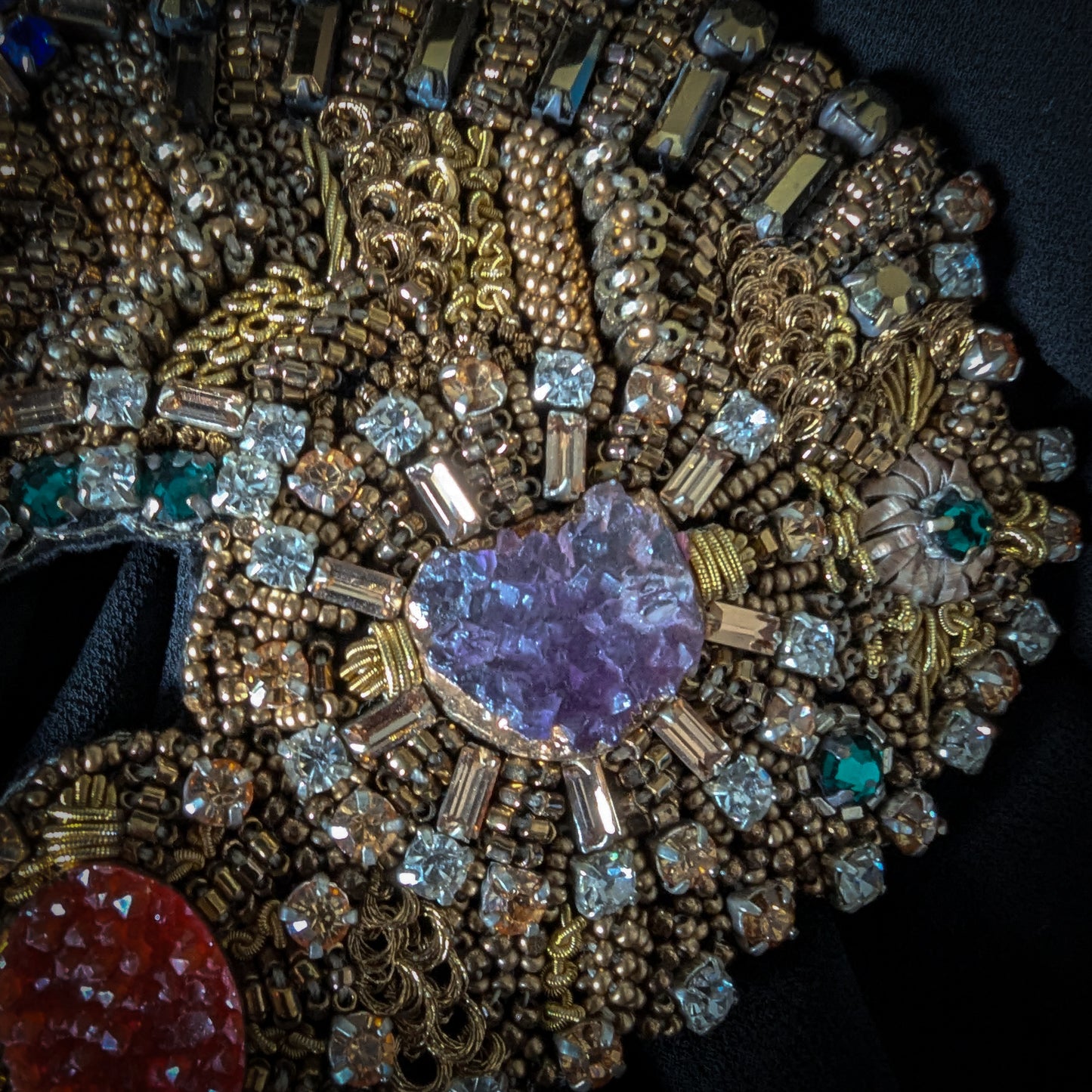 Heavy patch with gold embroidery, a purple heart-shaped amethyst, clear Swarovski crystals, and red and green gemstones.