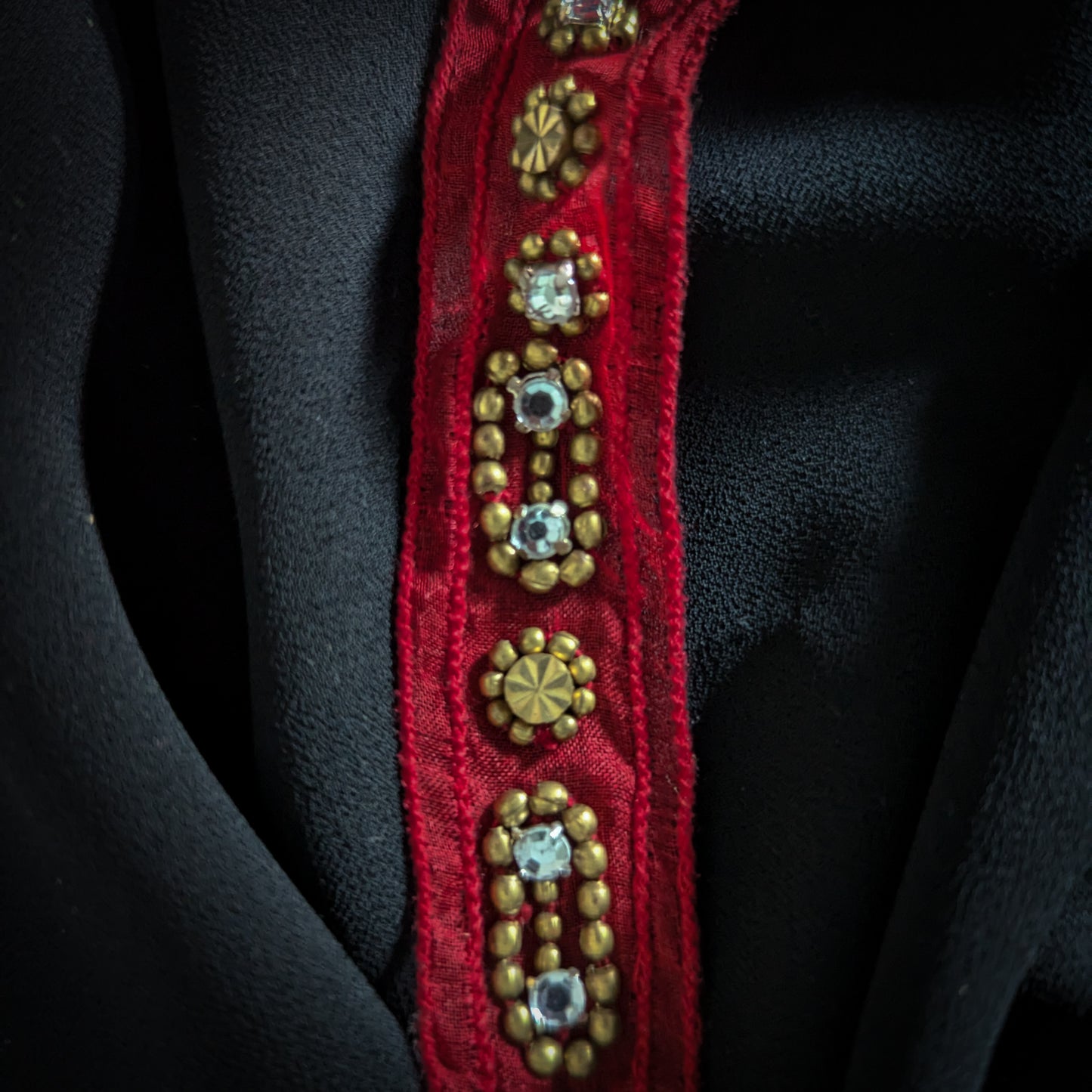 Red D&G decorative trim with gold beads and clear rhinestones on black fabric.