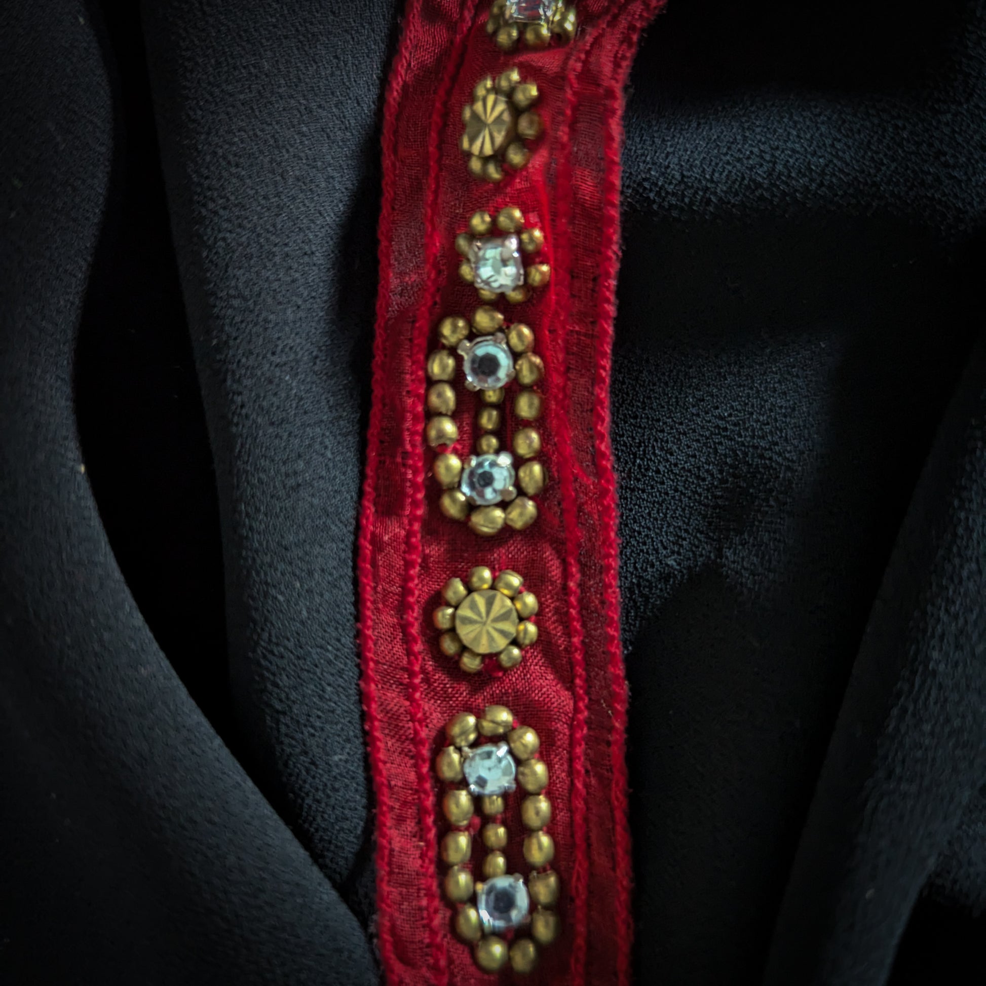 Red D&G decorative trim with gold beads and clear rhinestones on black fabric.