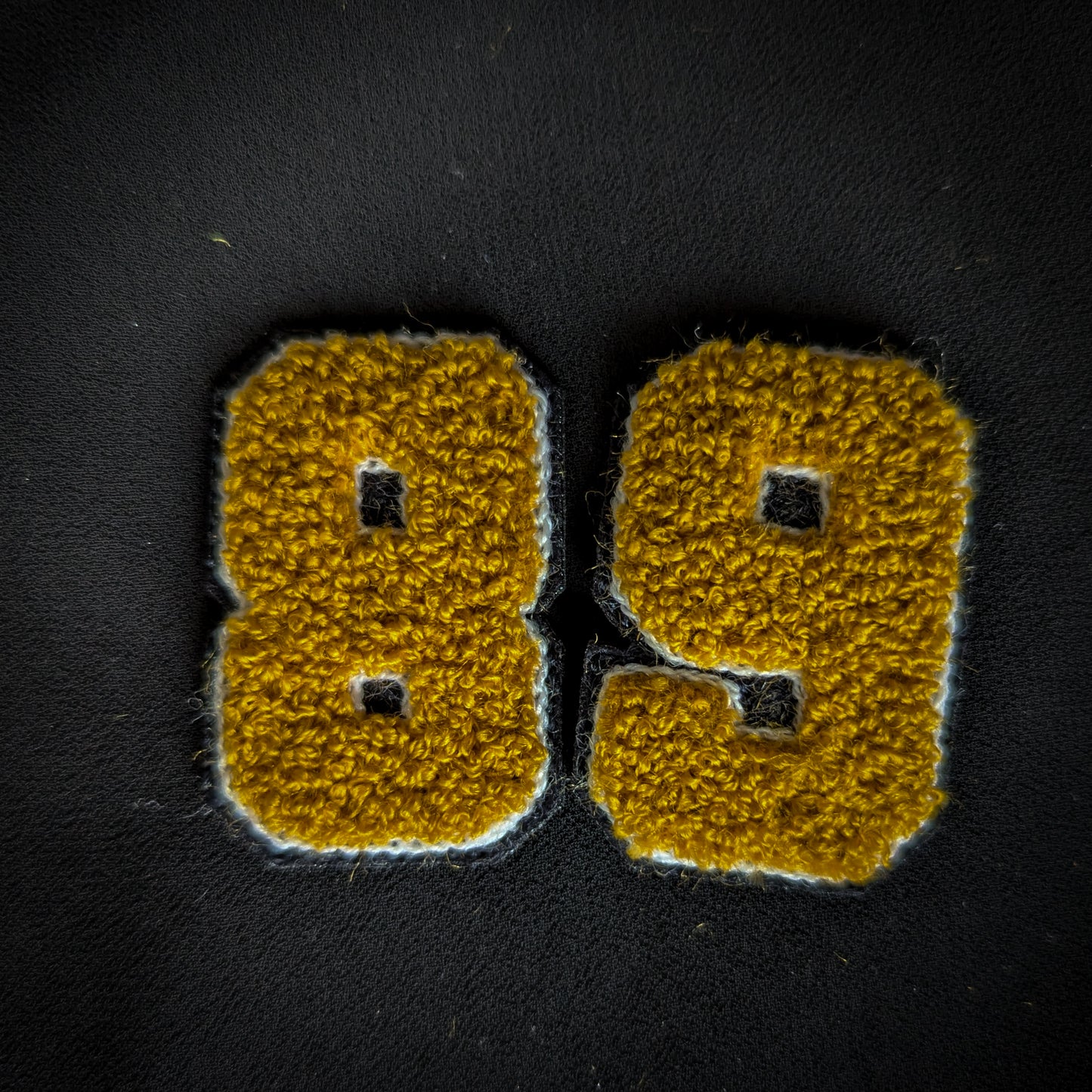 D&G vintage patch "89" (or "68") with yellow chenille numbers and white outline on black fabric.