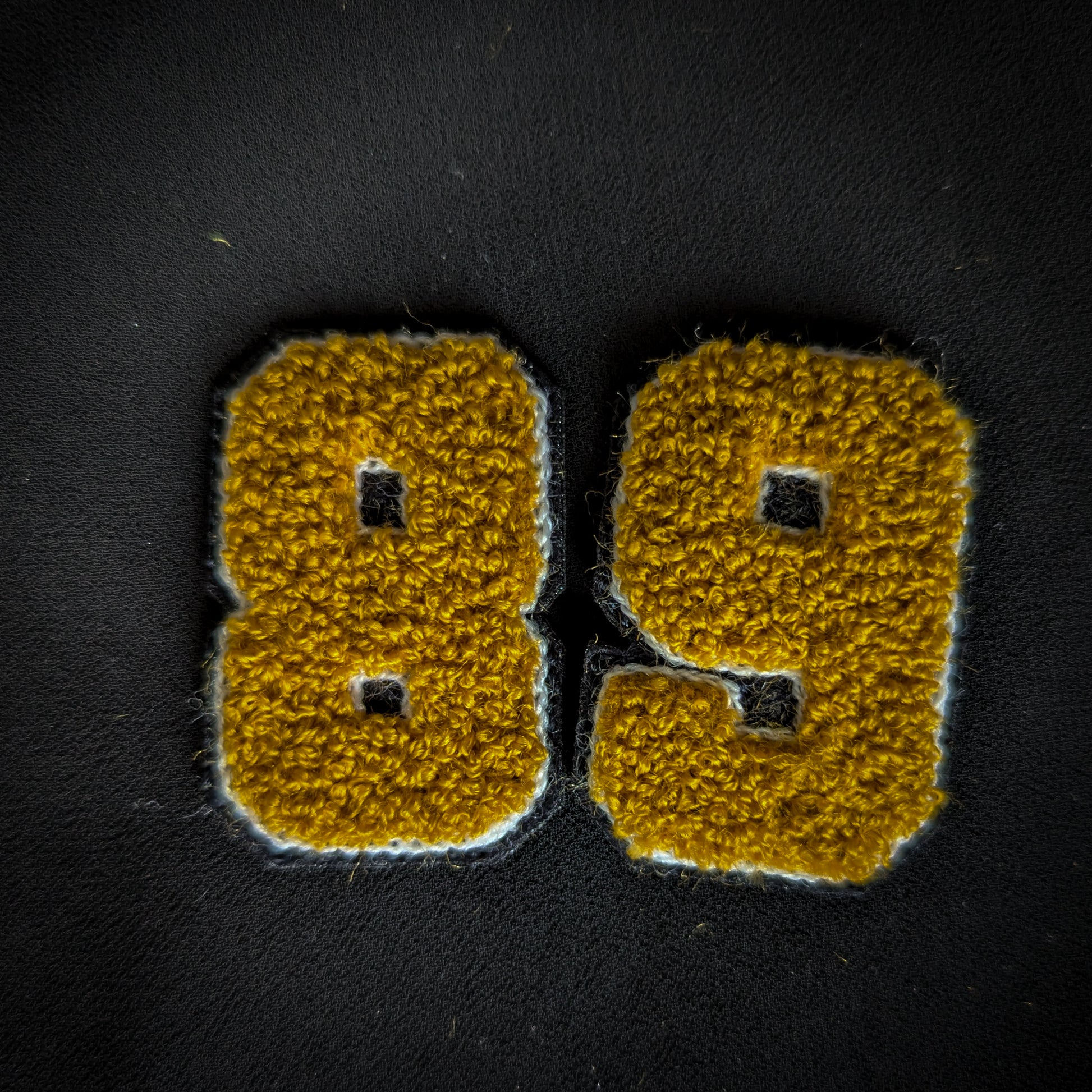 D&G vintage patch "89" (or "68") with yellow chenille numbers and white outline on black fabric.