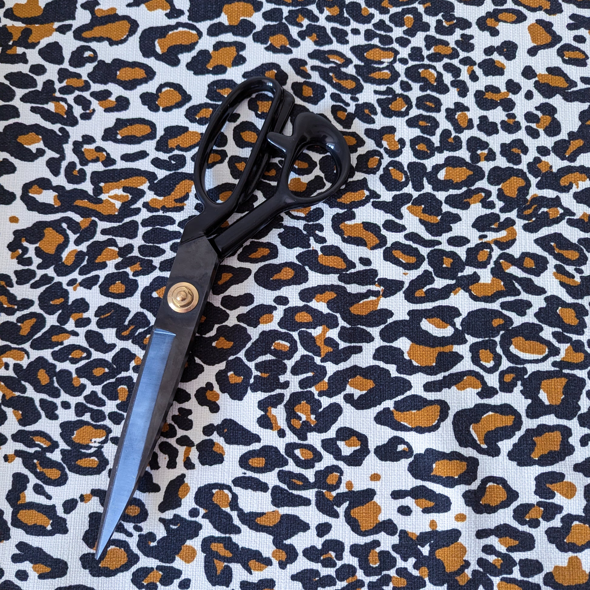 Deadstock cotton fabric with black and brown leopard print, featuring a pair of black scissors.
