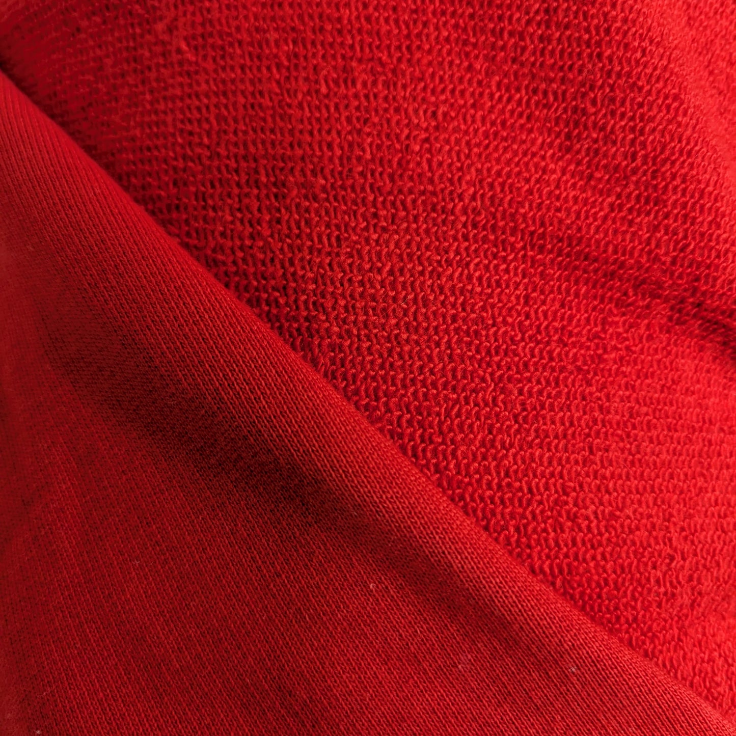 Tomato red deadstock Baumwollsweat fabric with a subtle sheen and textured knit.
