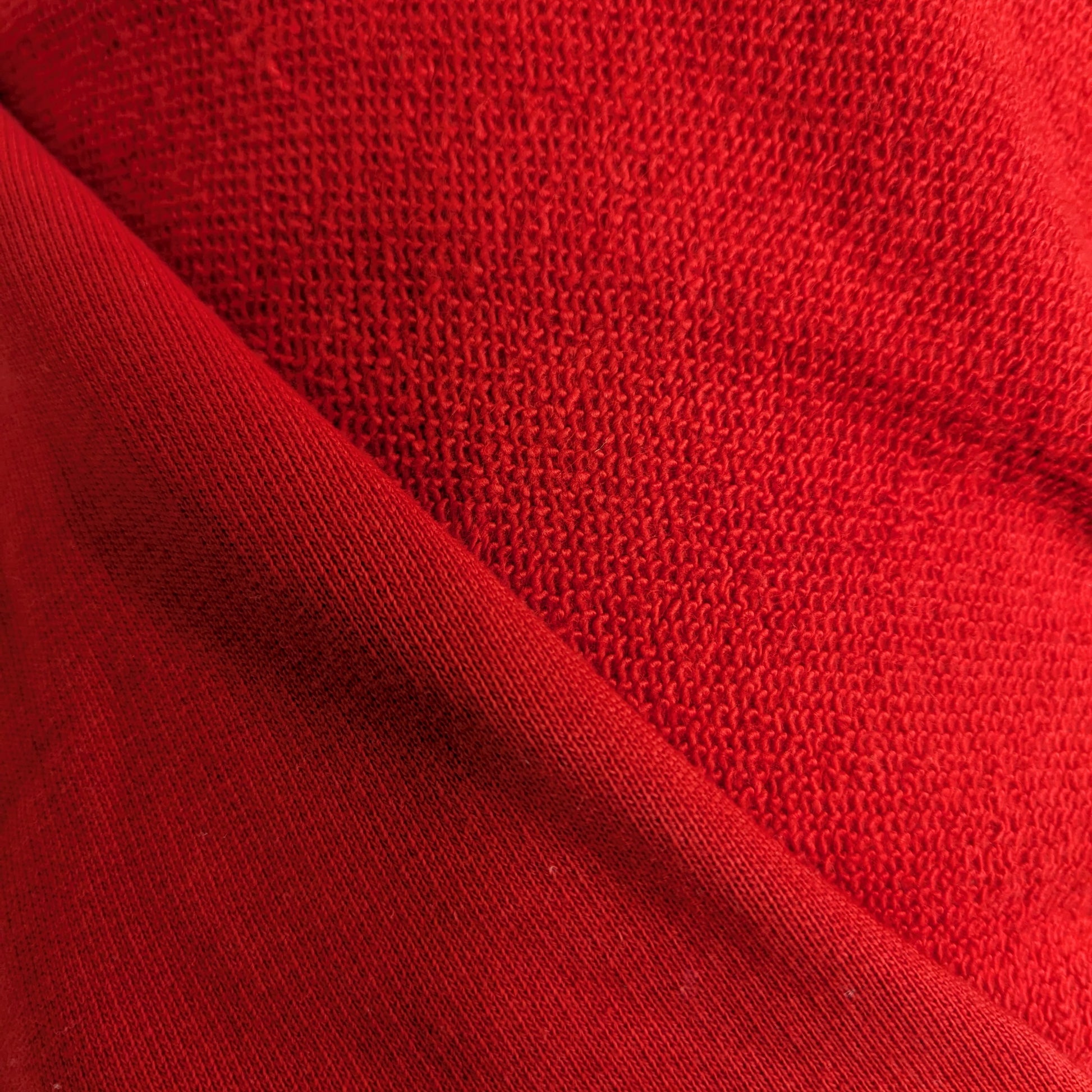 Tomato red deadstock Baumwollsweat fabric with a subtle sheen and textured knit.