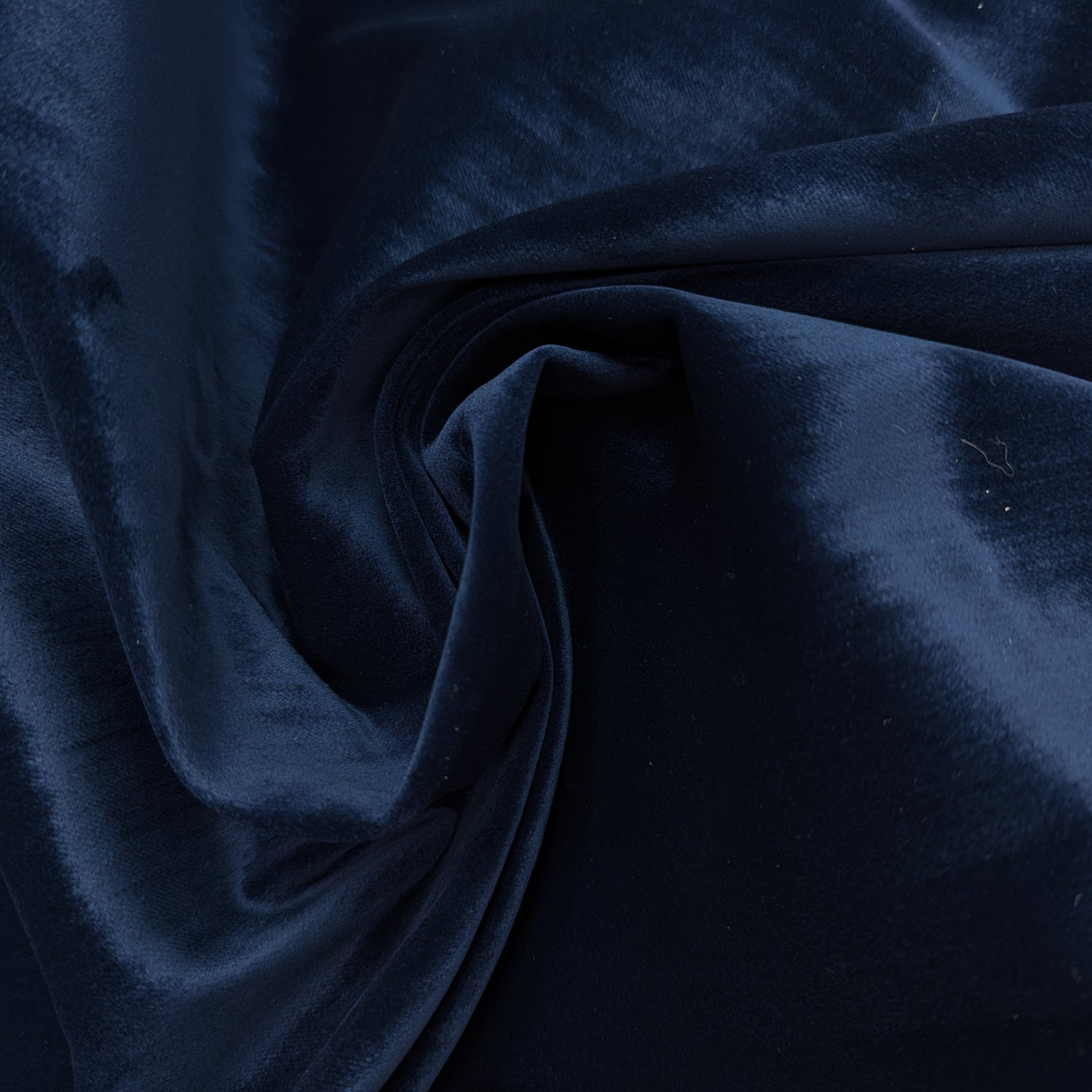 Dark blue velvet denim fabric, soft and robust, folded in a swirl.
