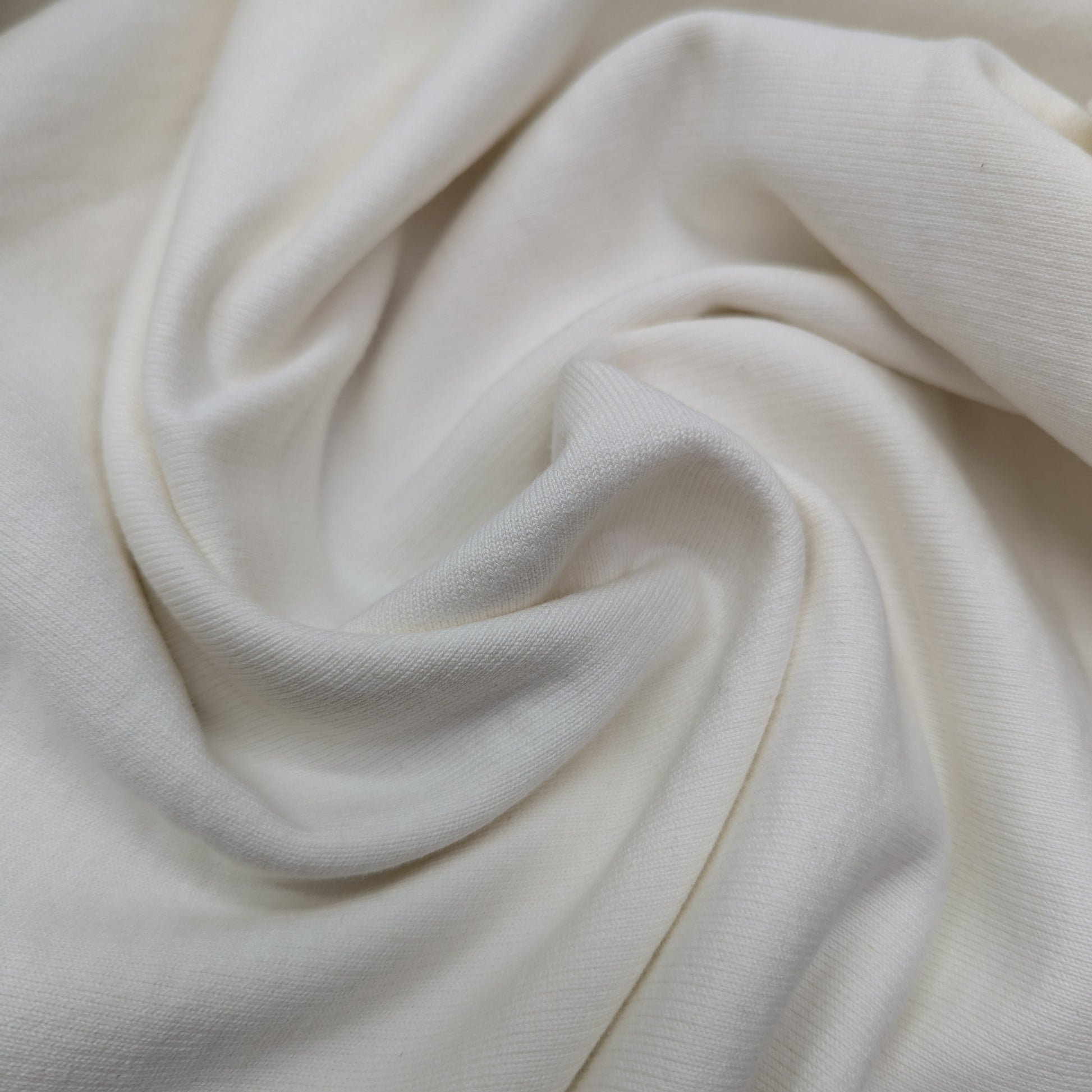 Soft, white cotton sweatshirt fabric, 190 cm wide, with gentle folds.