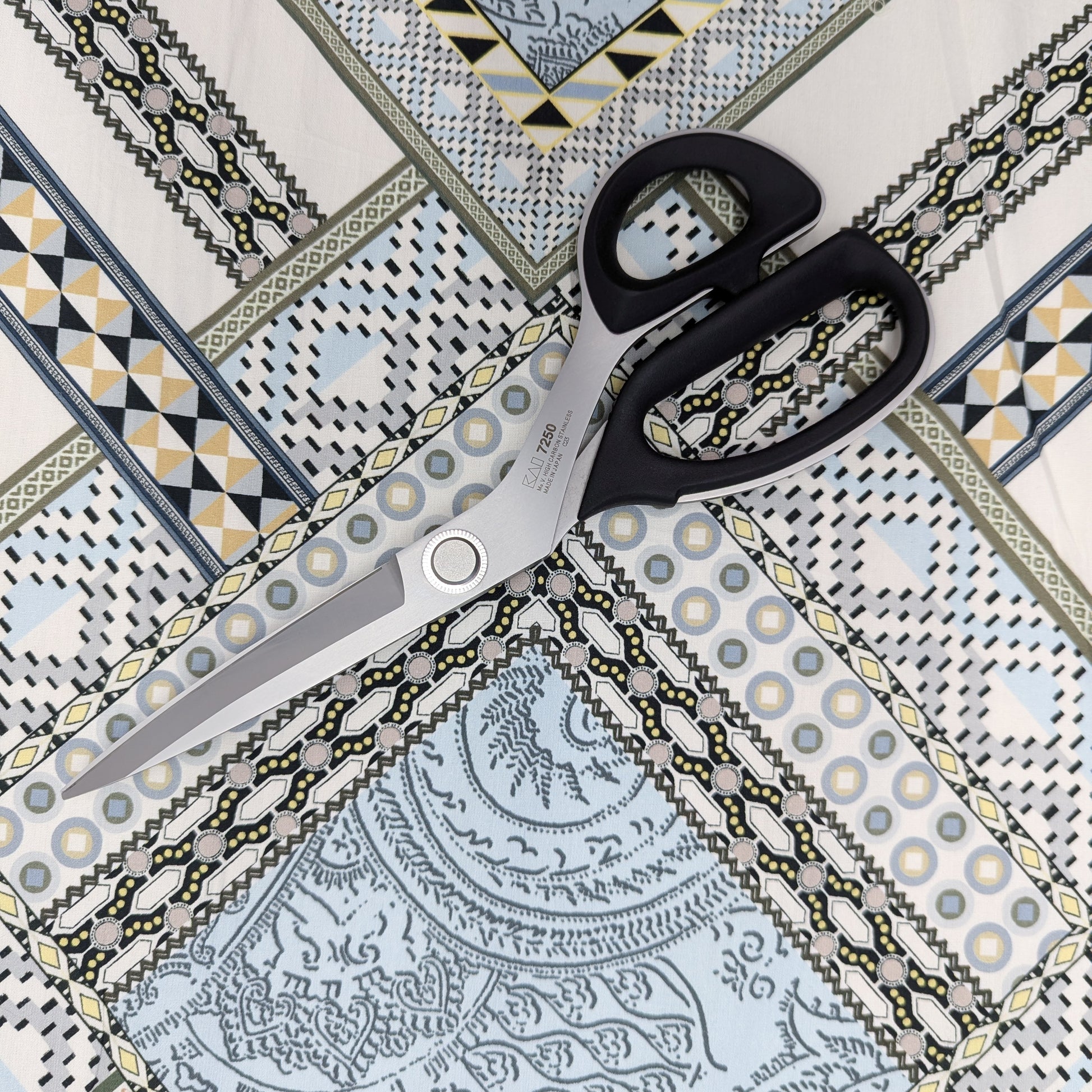 Multicolor E##o designer deadstock cotton poplin fabric with geometric and ornate patterns, scissors on top.