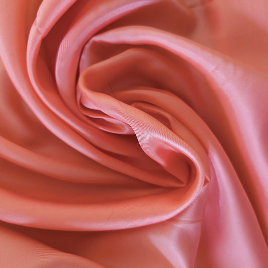 Swirling salmon pink viscose lining fabric, smooth and slightly shiny, ideal for deadstock projects.