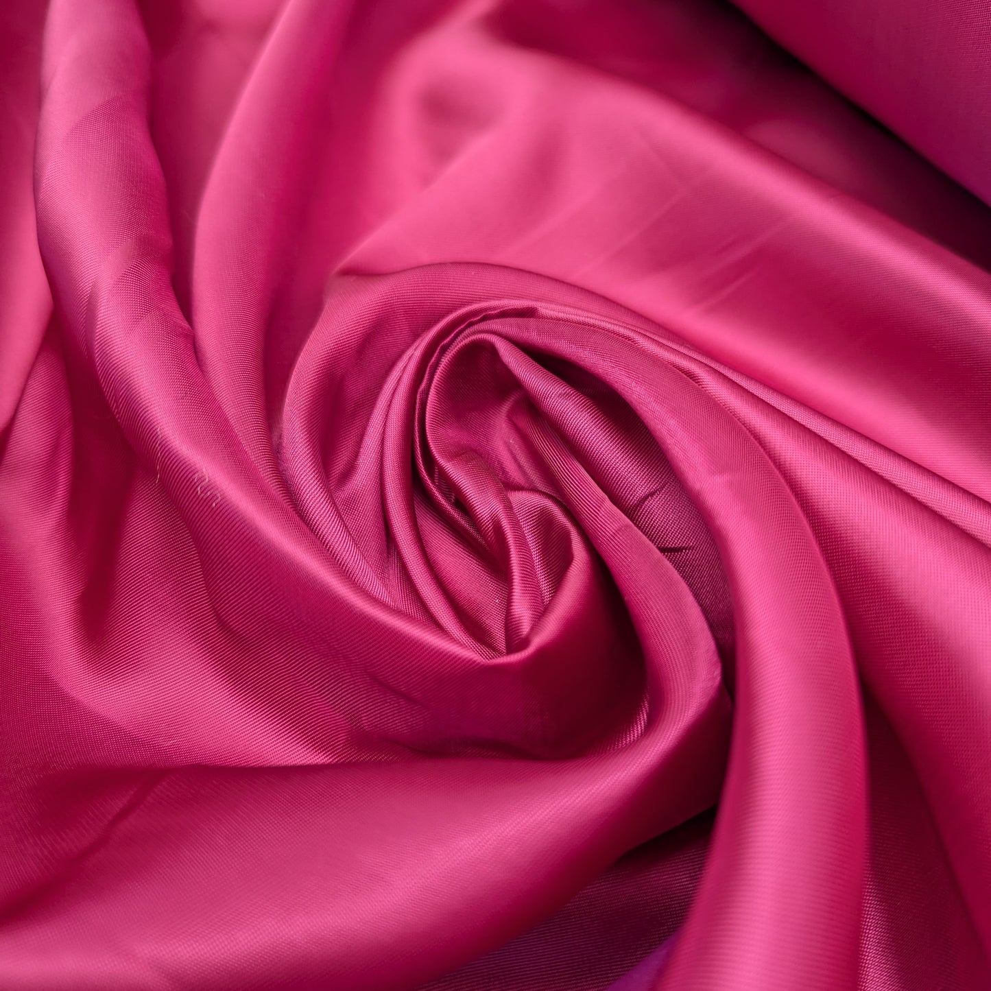 Smooth, magenta viscose lining fabric, deadstock from Alexander McQueen, draped in soft folds.