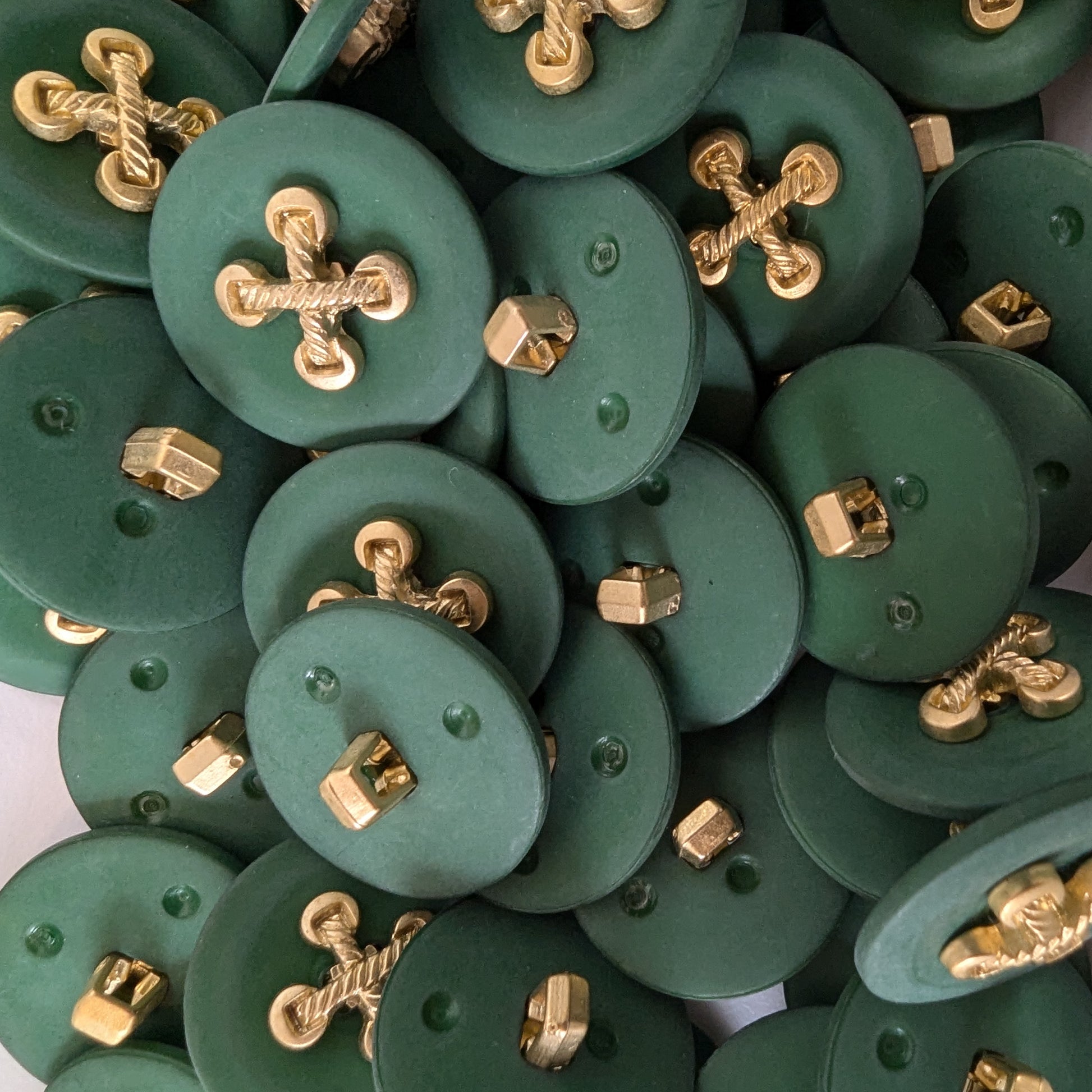 Green plastic buttons with gold metallic cross-shaped elements, approximately 2.3 cm.