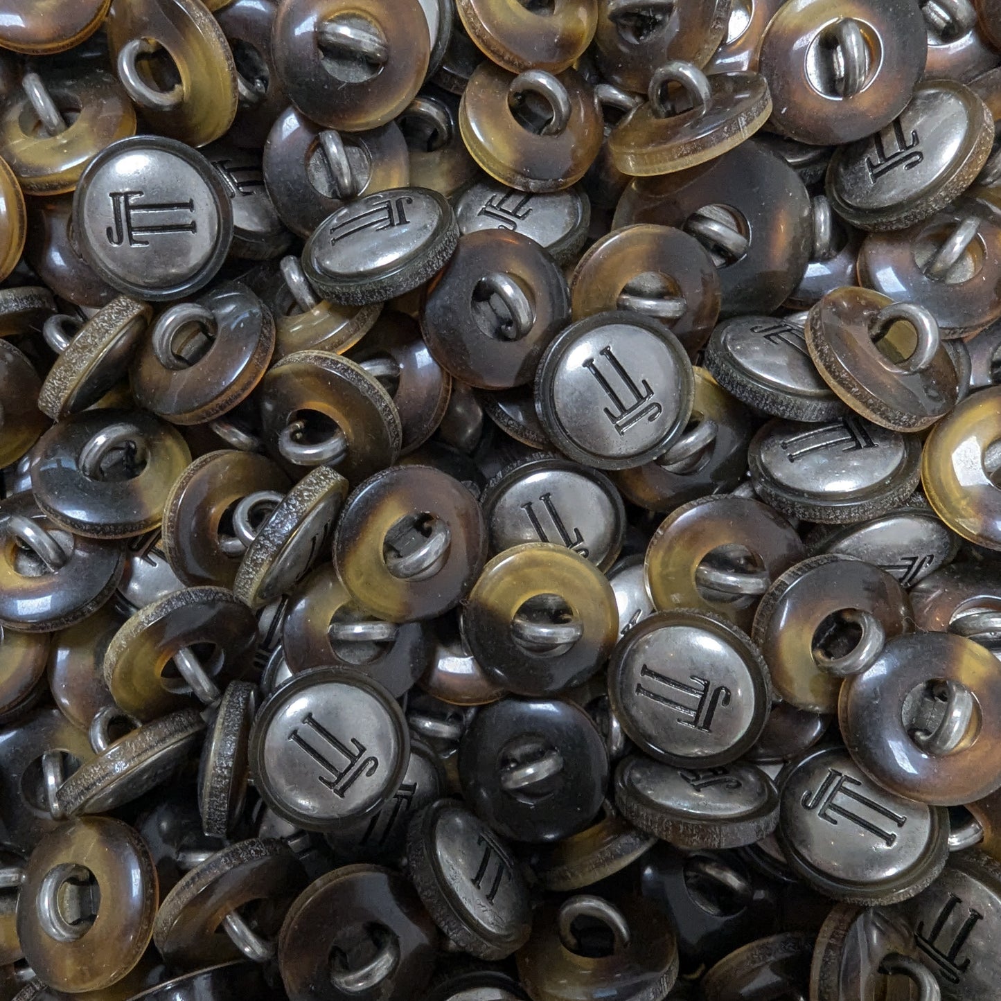 Collection of 1.5 cm round, two-tone brown tortoise shell and silver metal buttons with a "JL" monogram.