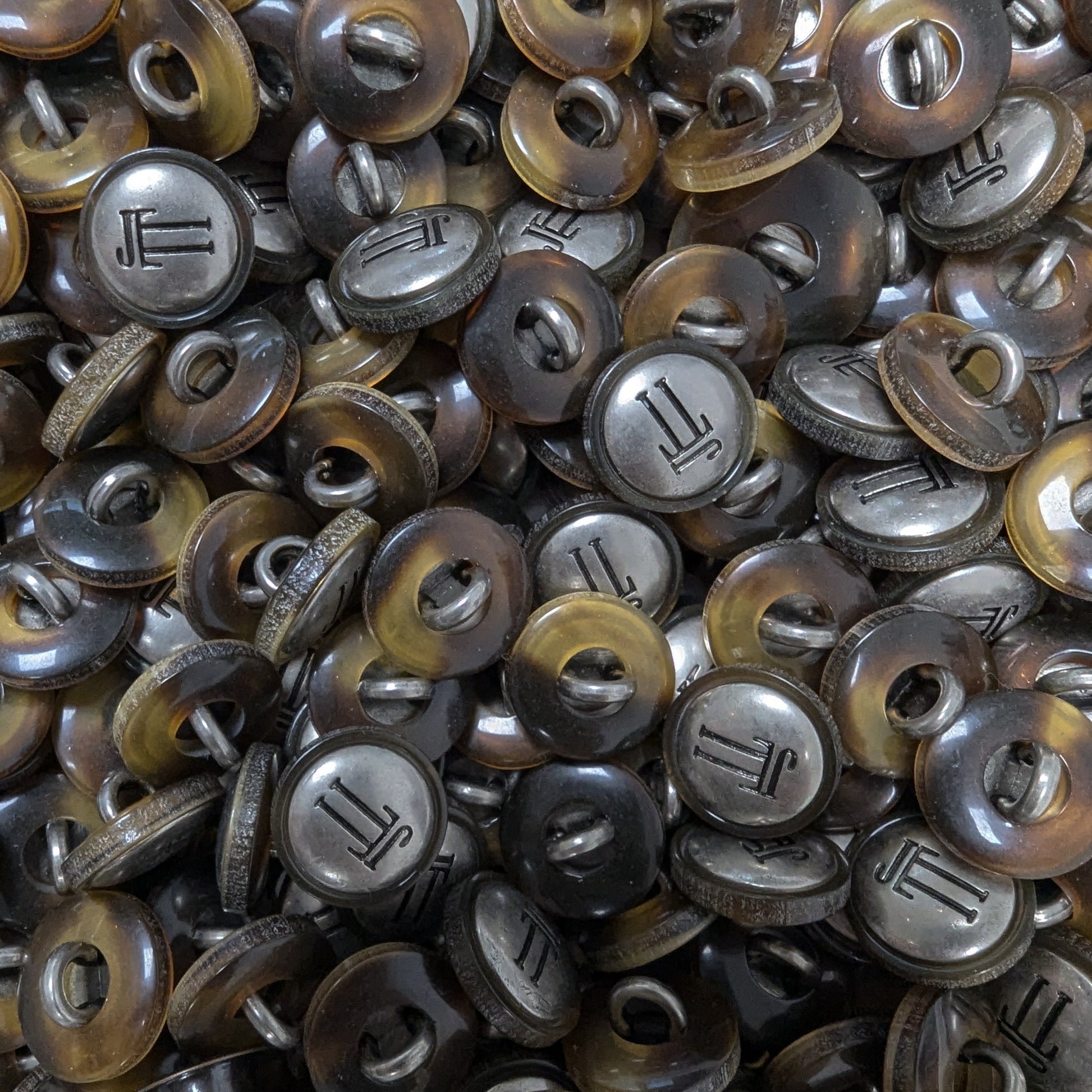 Collection of 1.5 cm round, two-tone brown tortoise shell and silver metal buttons with a "JL" monogram.