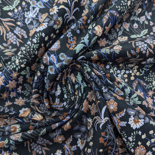 Black Feincord fabric with a vibrant multicolor millefleur floral pattern, draped in soft folds.