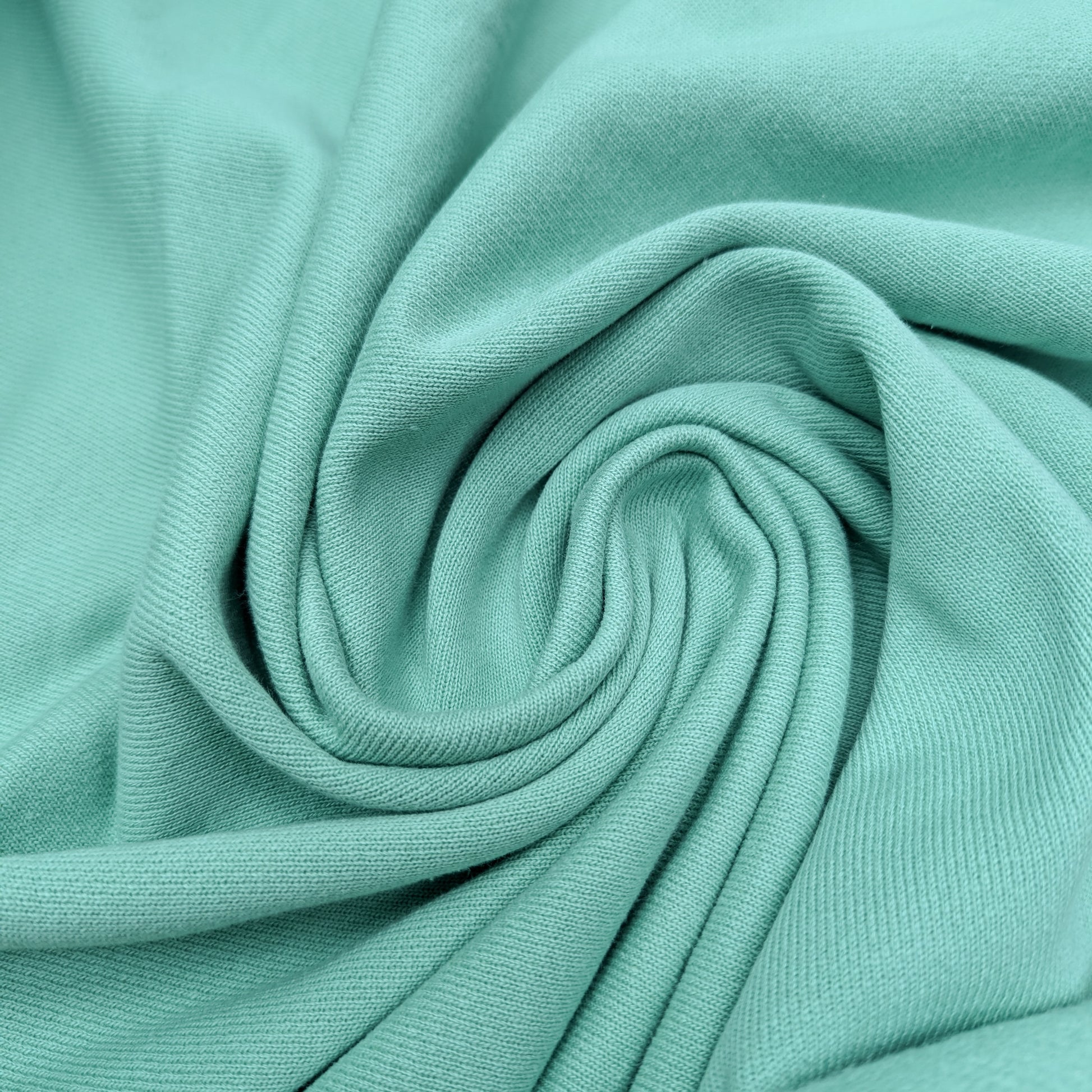 Deadstock pastel green sweatstoff fabric, 175cm wide, with soft texture and gentle folds.