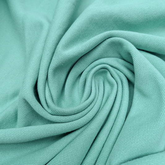 Deadstock pastel green sweatstoff fabric, 175cm wide, with soft texture and gentle folds.
