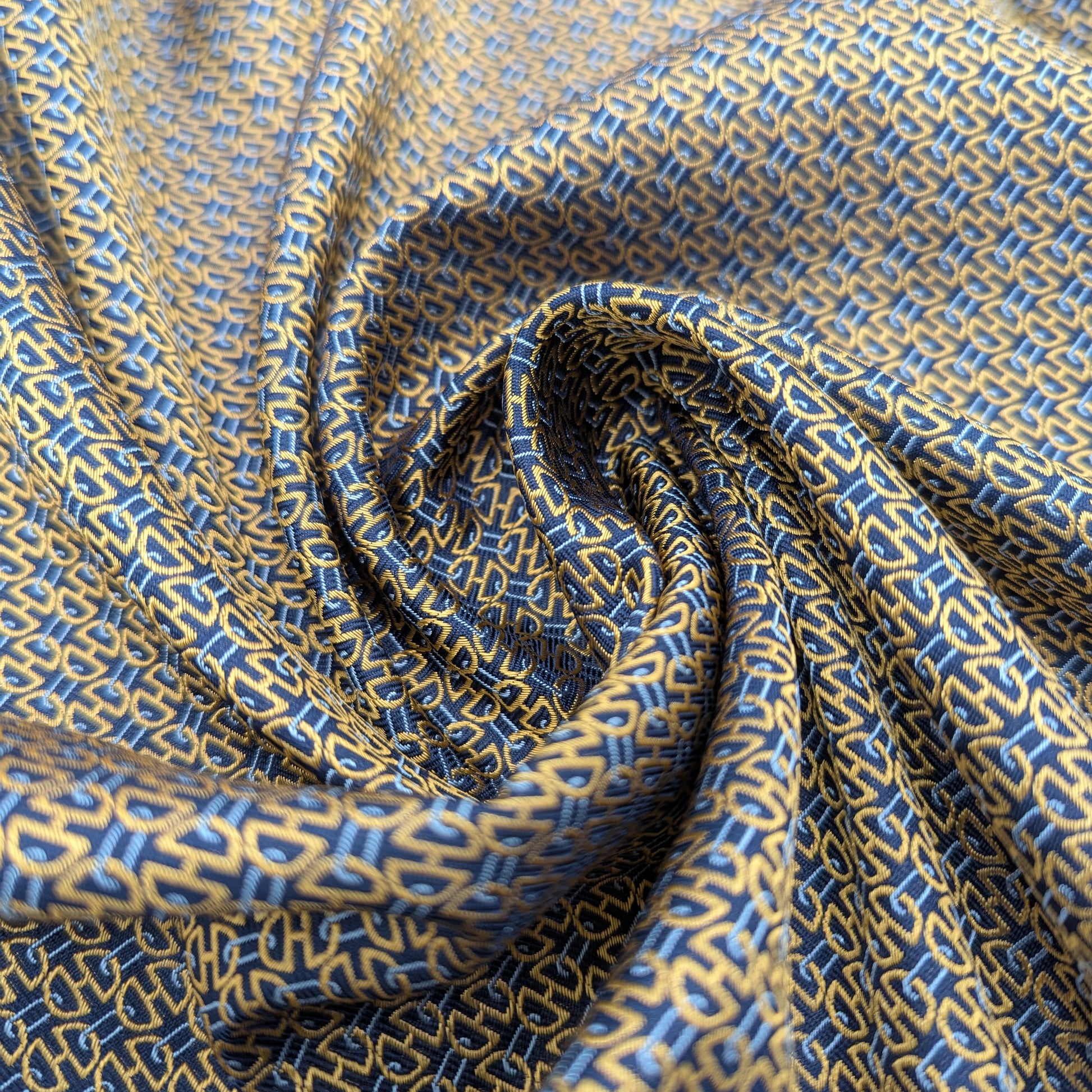 Deadstock blue and gold patterned silk fabric, elegantly draped with a subtle sheen.