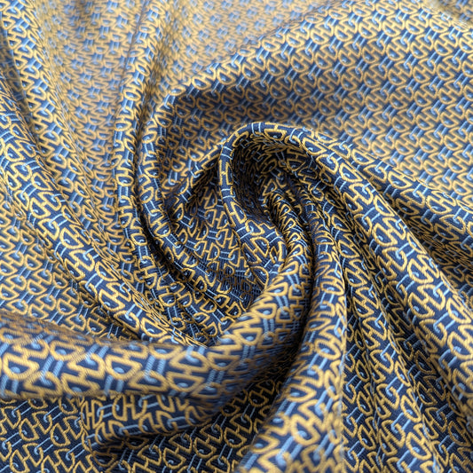 Deadstock blue and gold patterned silk fabric, elegantly draped with a subtle sheen.