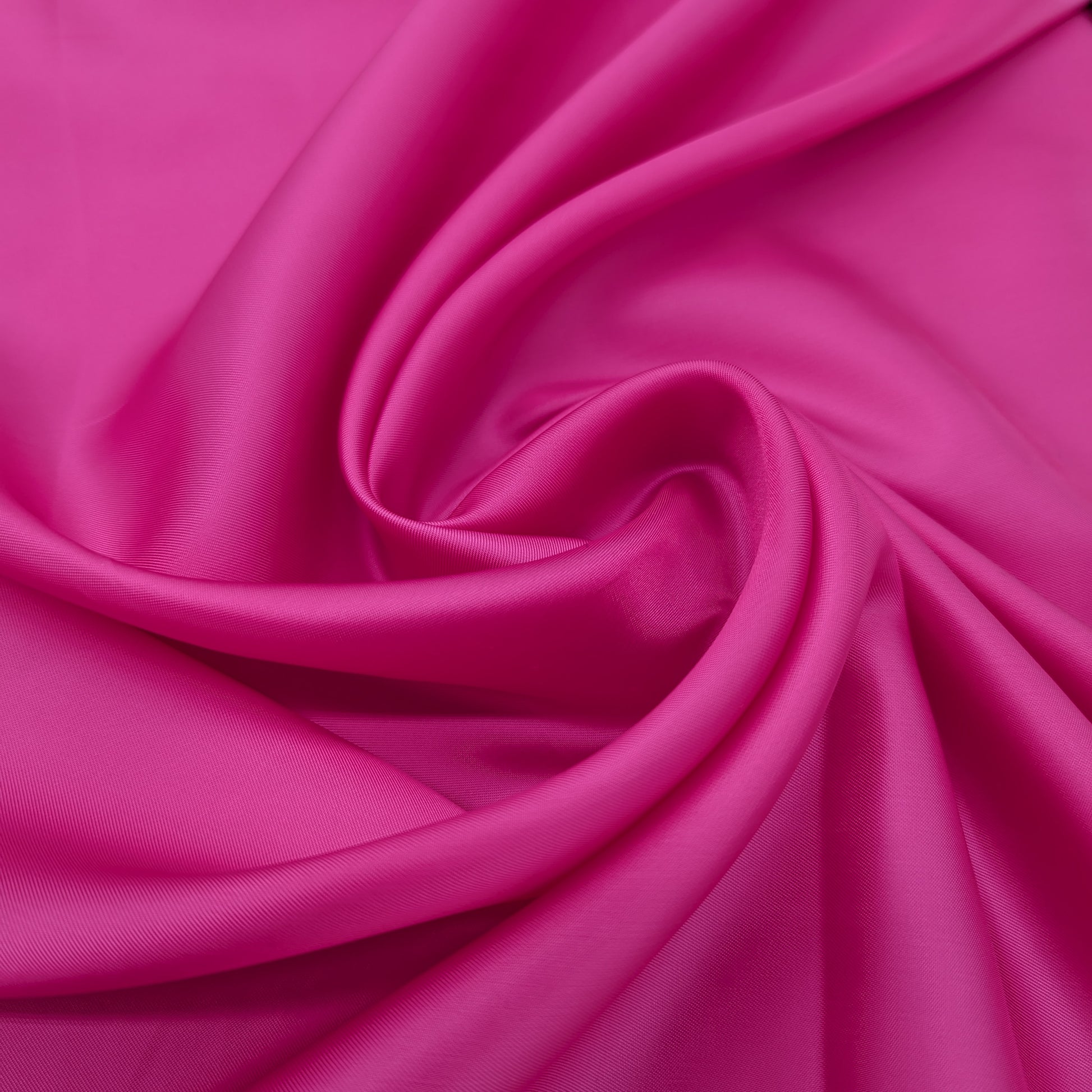 Vibrant fuchsia deadstock viscose lining fabric, smooth and light, draped in elegant folds.