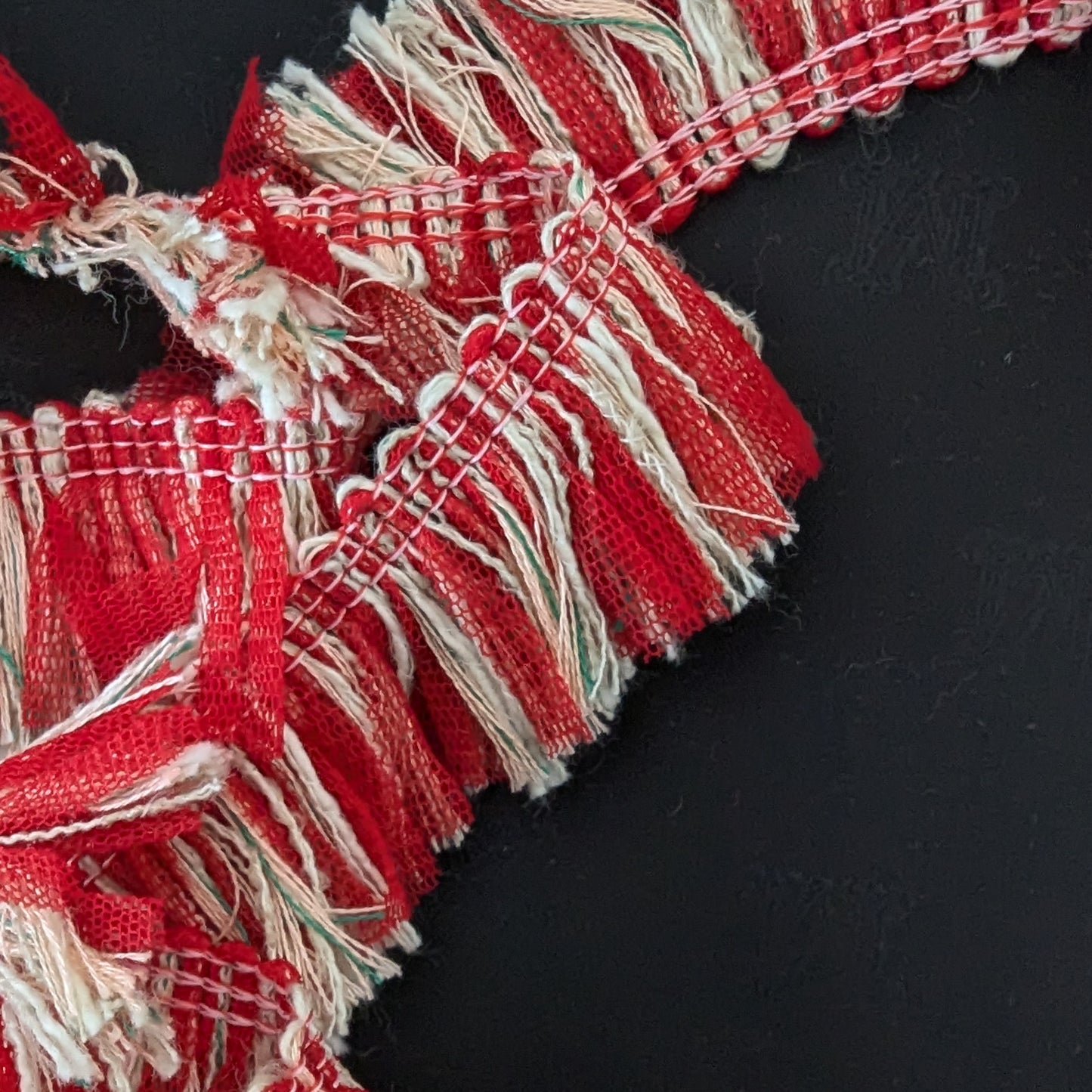 Red, white, and beige textured tweed fringe trim, 100 cm long, on a dark background.