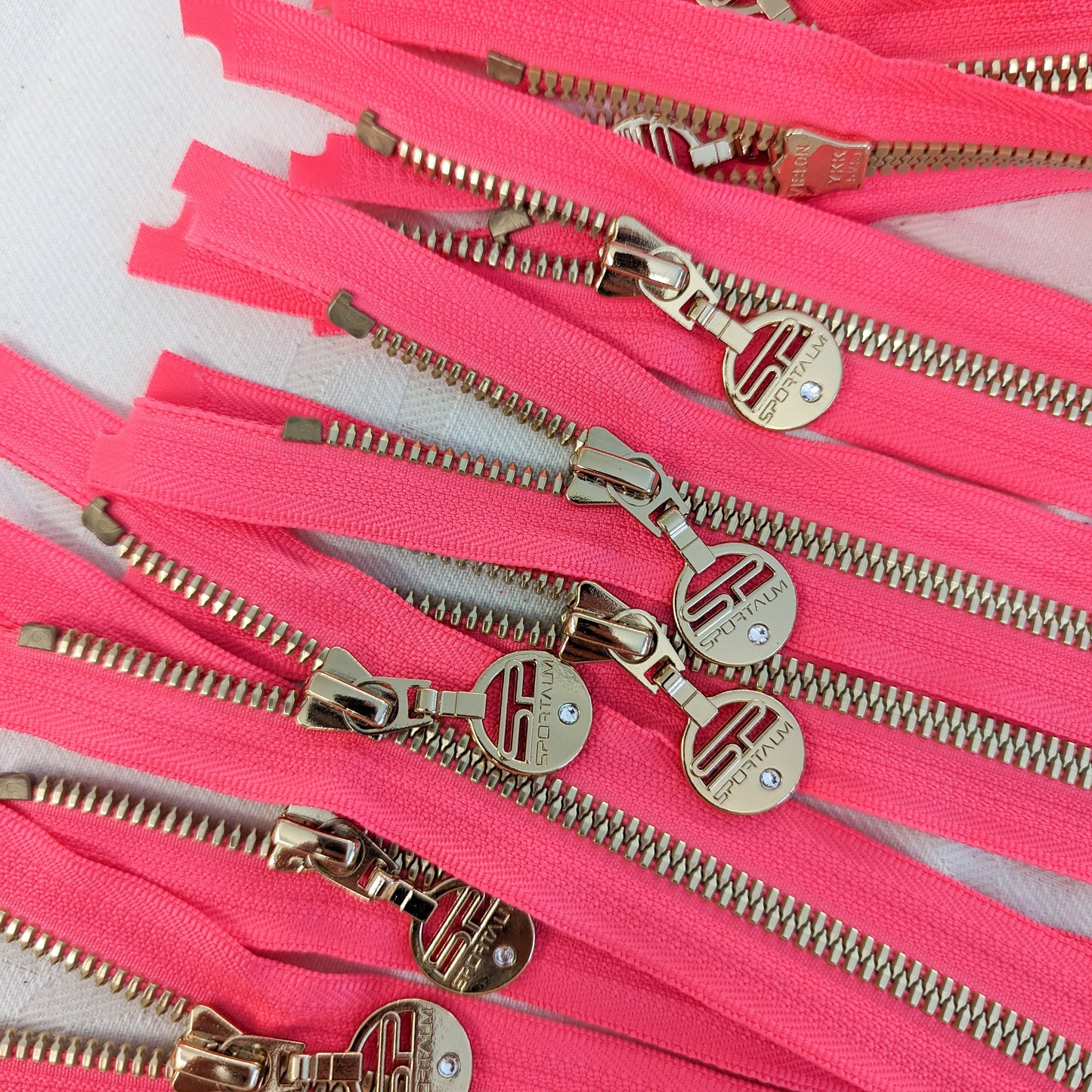 Neon pink zipper with golden metal teeth and designer pullers, 68 cm.