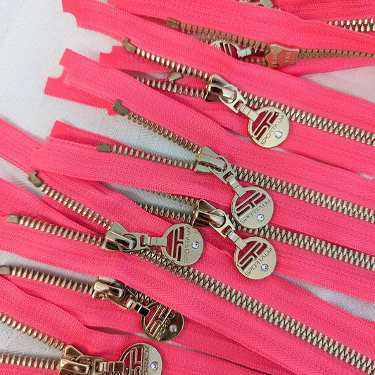 Neon pink zipper with golden metal teeth and designer pullers, 68 cm.