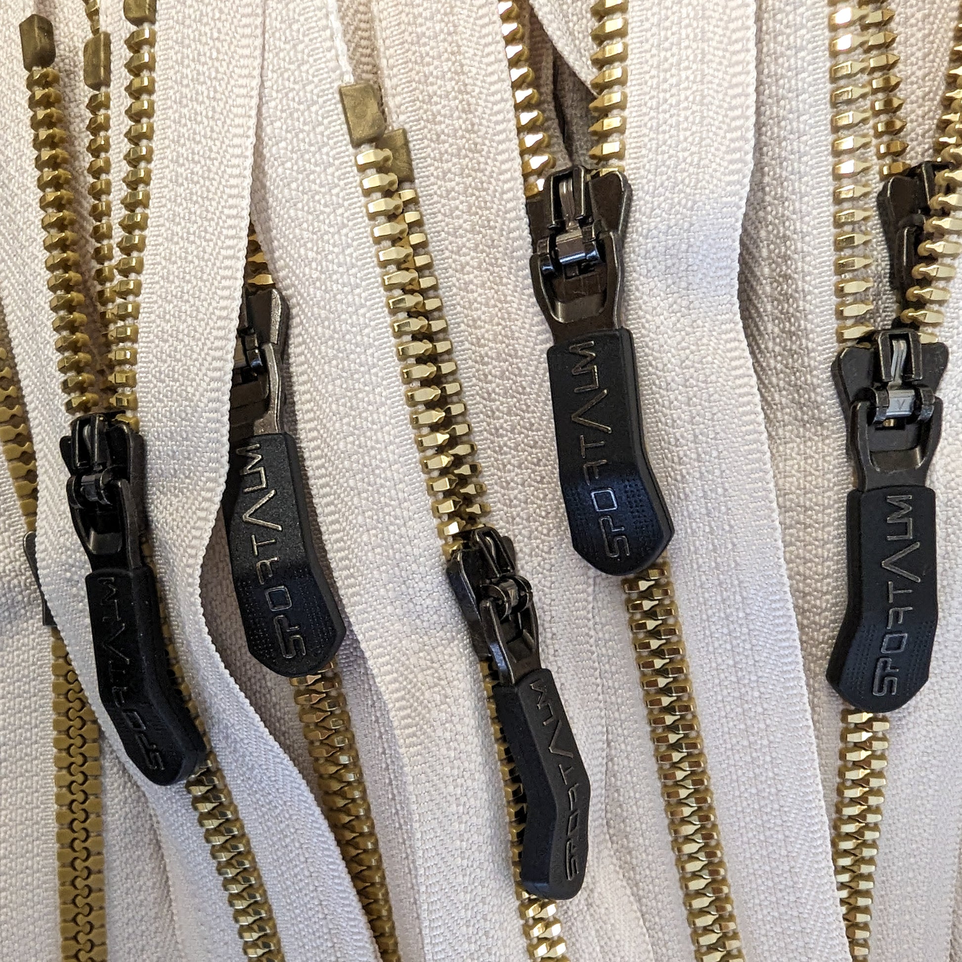 Cream zipper with golden metal teeth and black "SPORTALM" designer pullers.