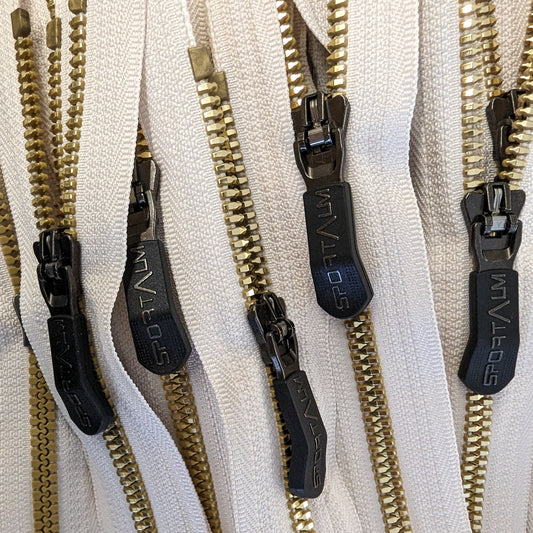 Cream zipper with golden metal teeth and black "SPORTALM" designer pullers.