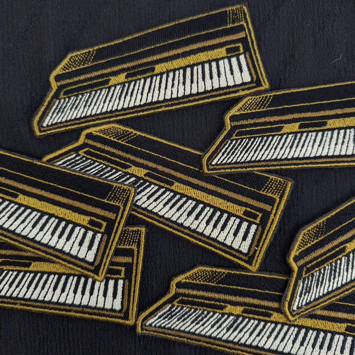 Black and gold embroidered piano keyboard patches made from designer deadstock, 10.5x3.5cm.