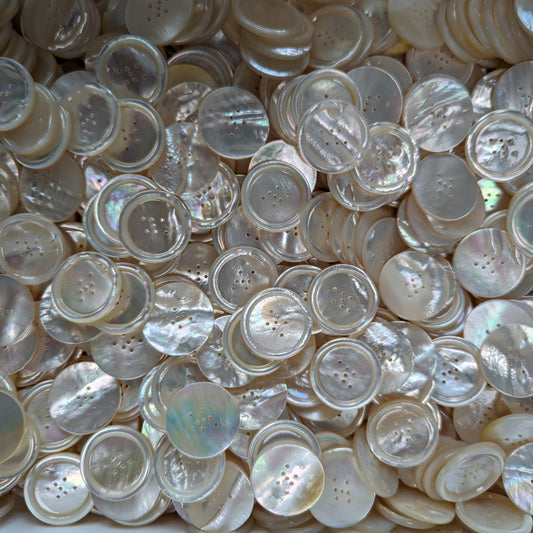 Pile of iridescent mother-of-pearl buttons, approximately 2.5 cm, each with 7 holes.