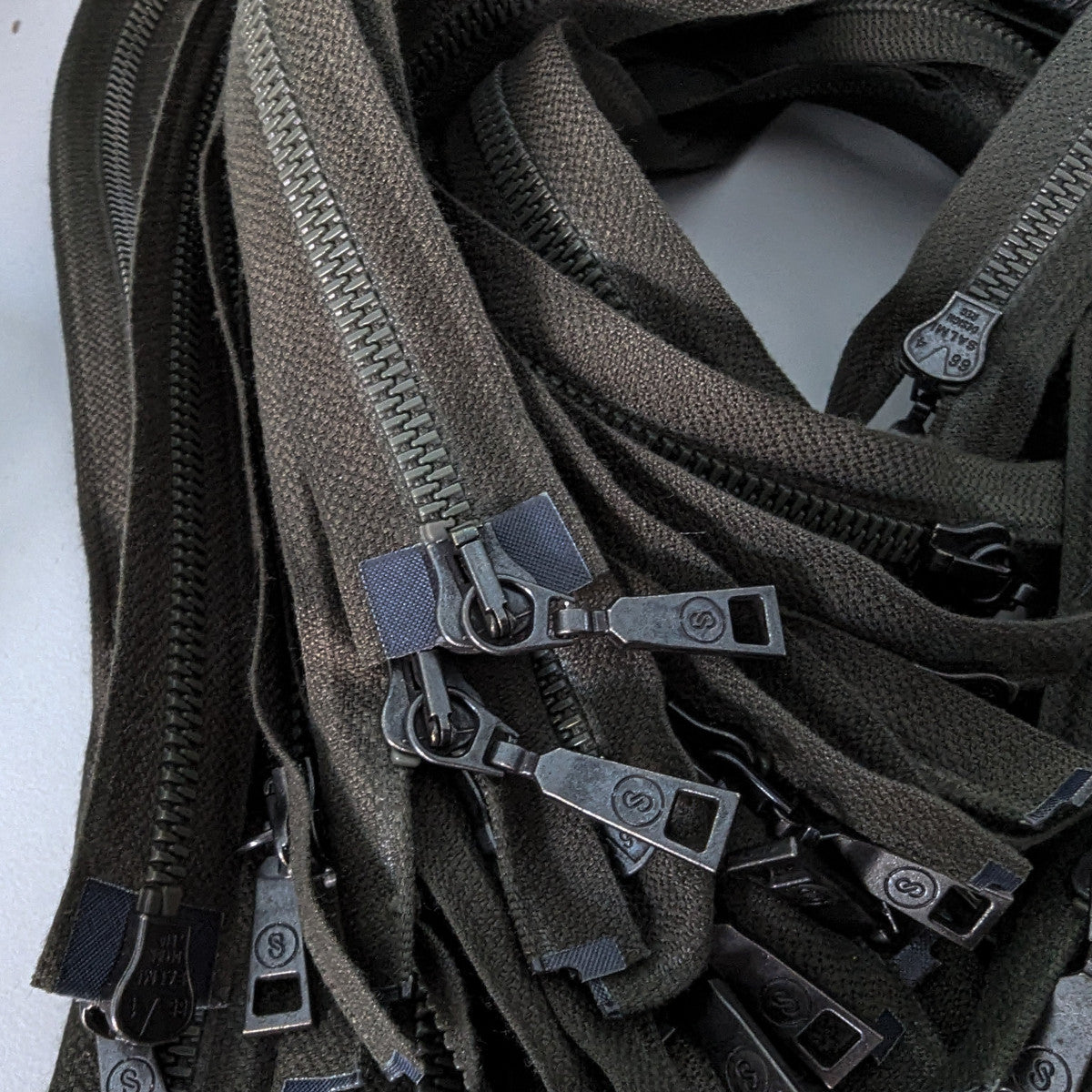 Dark green two-way zipper, 60 cm, with multiple metal sliders and pulls.