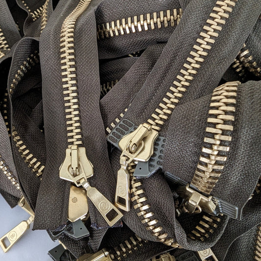Dark green two-way zippers with shiny gold metal teeth and elegant pulls, 62 cm, separable.