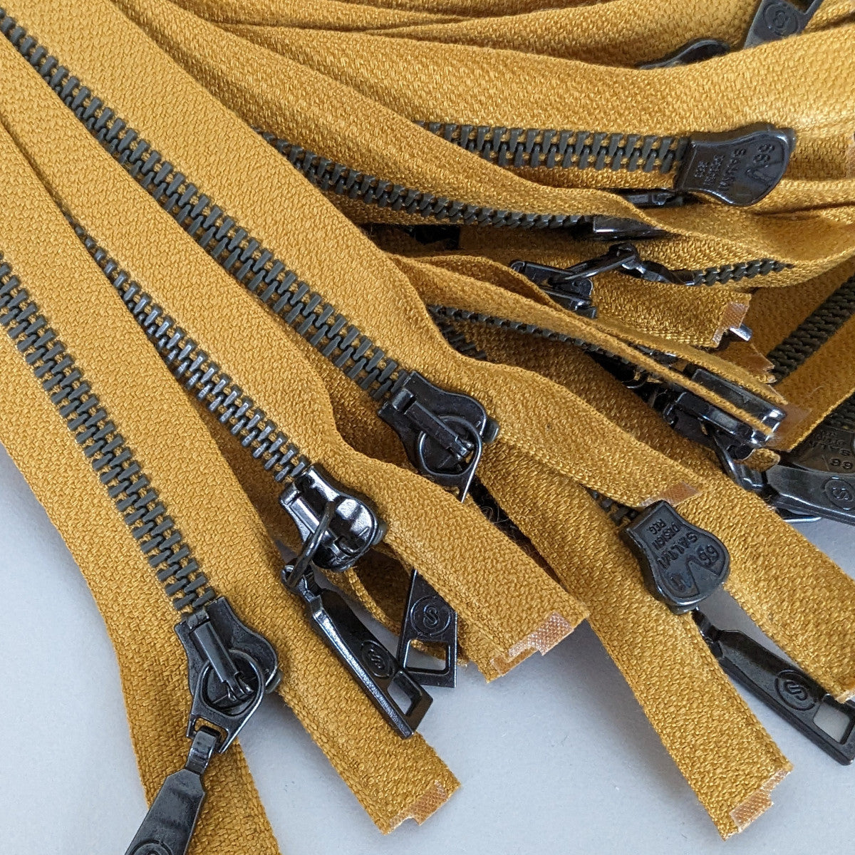 Mustard yellow two-way zipper, 60 cm, with dark grey teeth and ergonomic pulls.