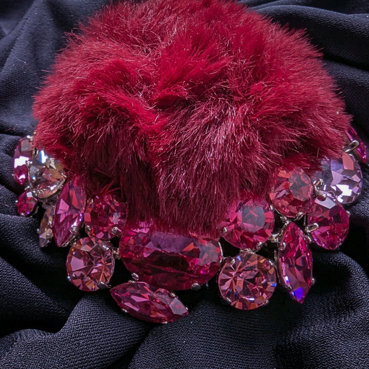 DG ornament: burgundy fur pom-pom with pink and rose Swarovski crystals on black fabric.