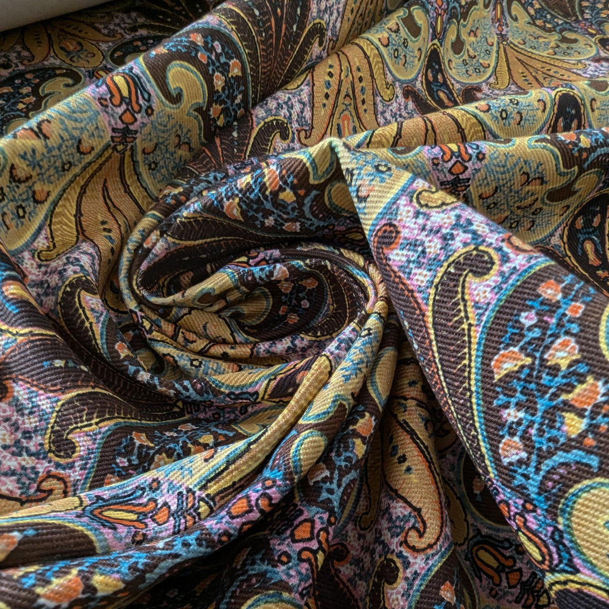 E##o deadstock denim fabric with a vibrant paisley print in brown, gold, blue, and orange.