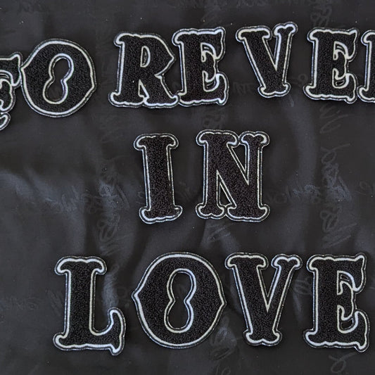 Black chenille "FOREVER IN LOVE" patch set with white embroidered outlines, on a dark fabric.