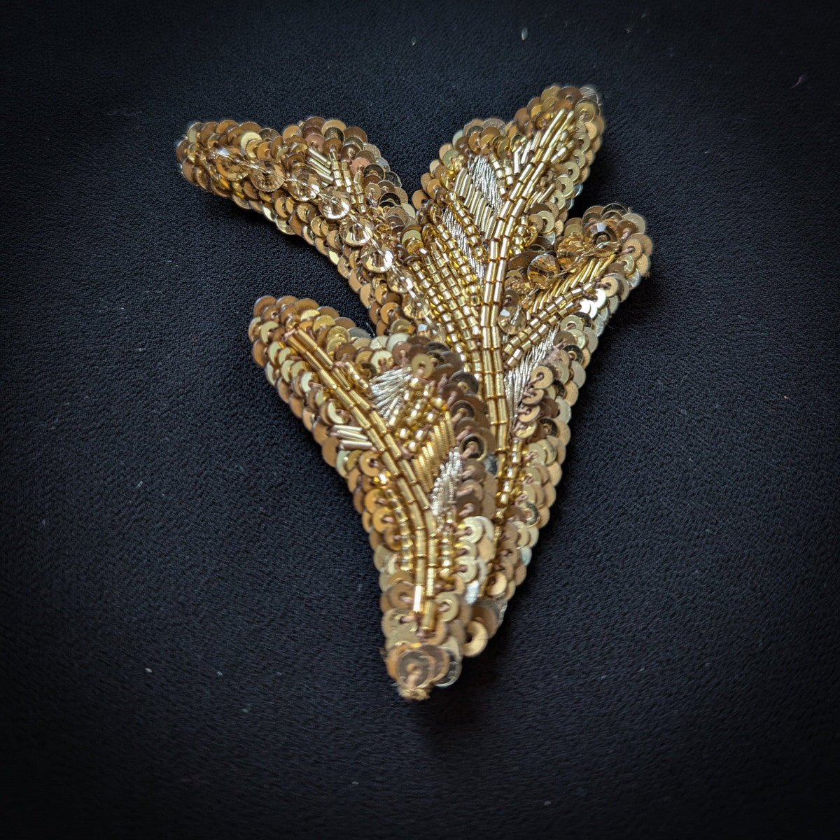 D&G gold sequin and bead embroidered leaf-shaped patch, 7x9 cm, on black fabric.