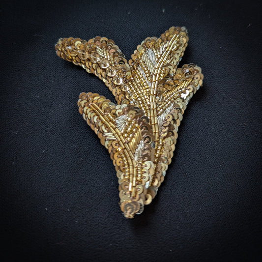 D&G gold sequin and bead embroidered leaf-shaped patch, 7x9 cm, on black fabric.