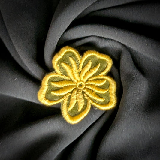 Embroidered floral patch, 5x5 cm, with yellow and olive green threads on dark fabric.