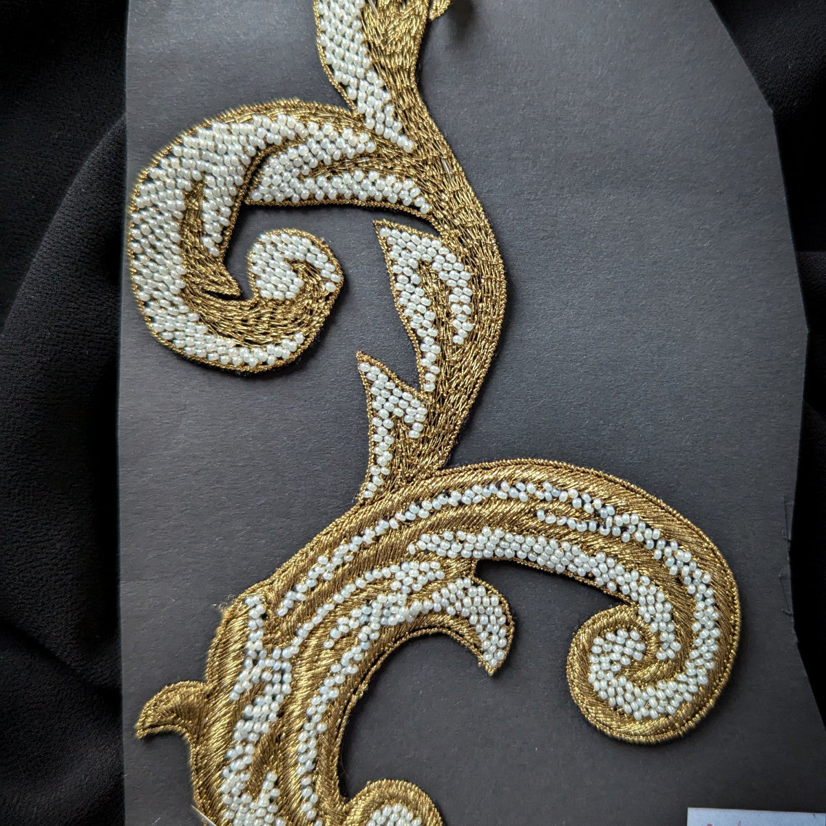 D&G gold metallic embroidered patch with white pearls, 9x14 cm, on a dark background.