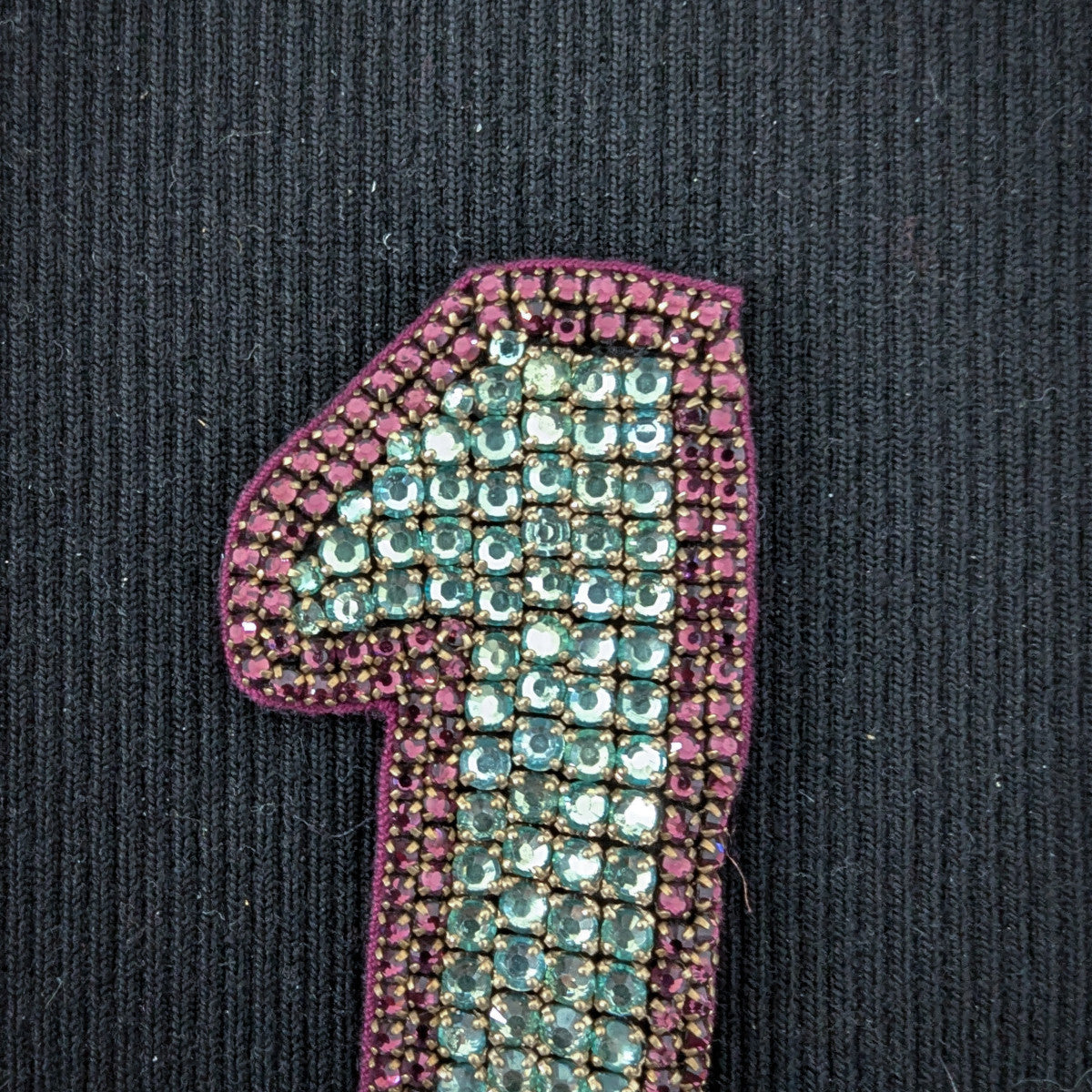 D&G "1" patch with turquoise and magenta pearl embroidery on black fabric.