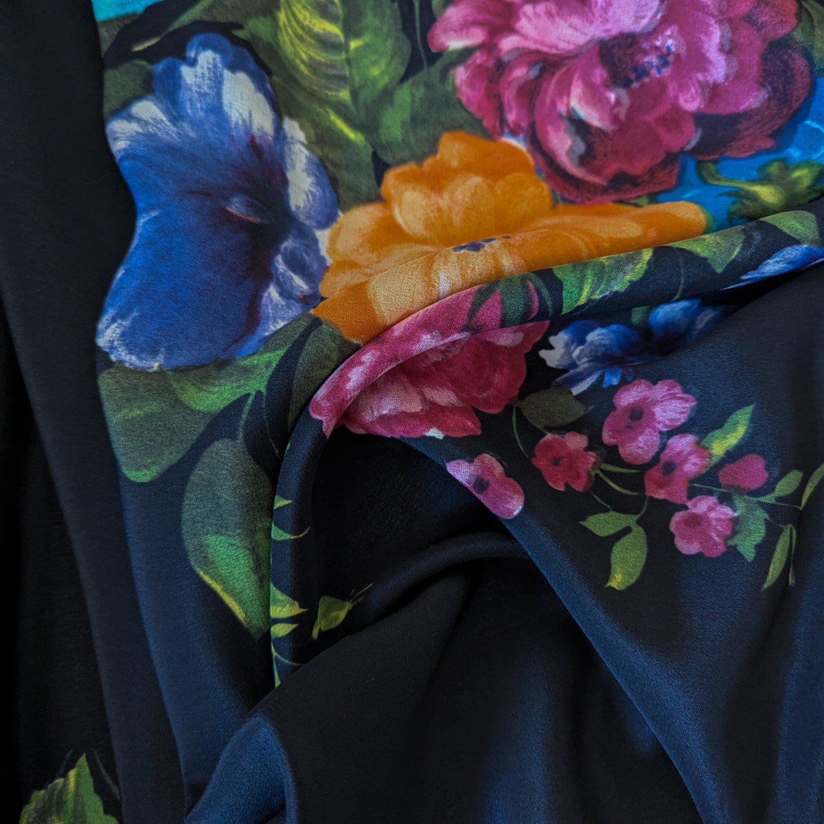 Deadstock G*cci Seidenchiffon fabric, 140 cm wide, with vibrant floral print on a dark background.