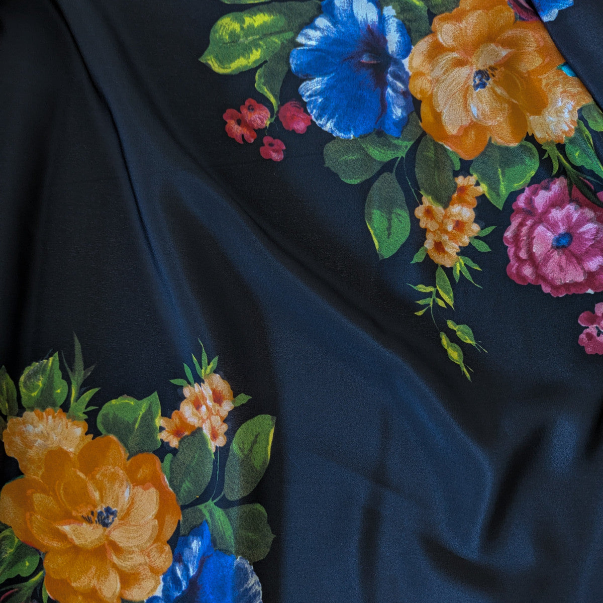 Dark blue silk chiffon fabric with vibrant orange, blue, and pink floral print.