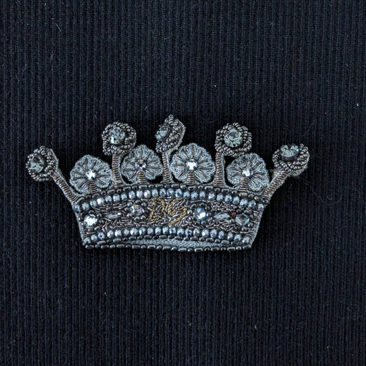 D&G embroidered crown patch with silver beads, pearls, and jewels on black fabric.