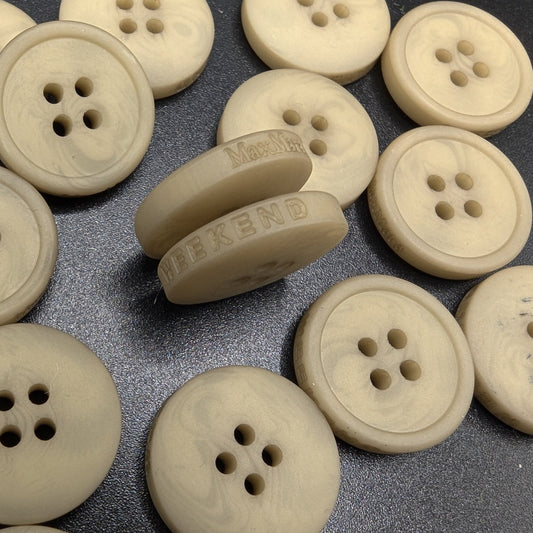 Creamy beige 4-hole buttons, some engraved with "MaxMara Weekend" logo, on a dark surface.