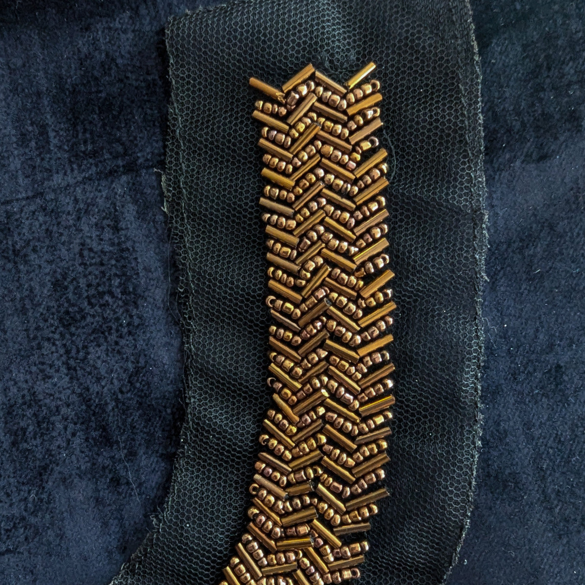 D&G black mesh patch with rows of bronze pearl beads in a chevron pattern.
